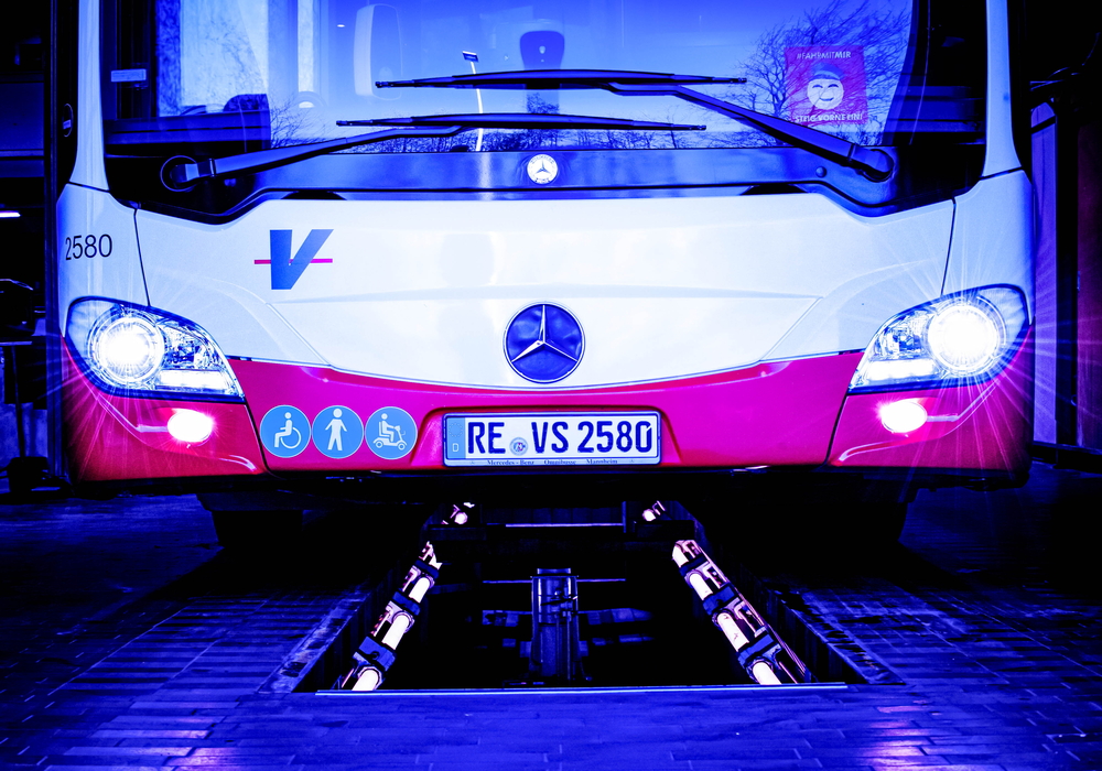 Untere Front eines Busses mit eingeschalteten Scheinwerfern. In der Mitte ist das Mercedes-Logo zu sehen.